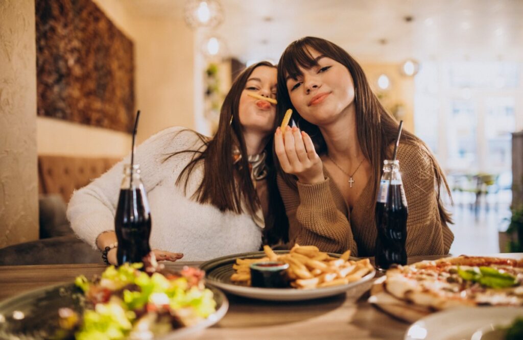 two girls friends eating pizza in cafe